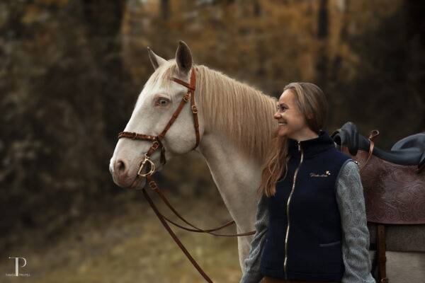 Lisa Jost präsentiert ihre neue Reitkunstliebe Weste stehend neben Jaguar von vorne